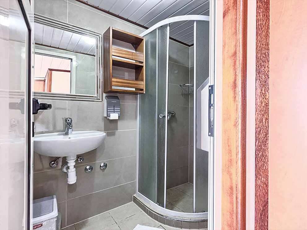 Badezimmer mit Eck-Duschkabine und Waschbecken.