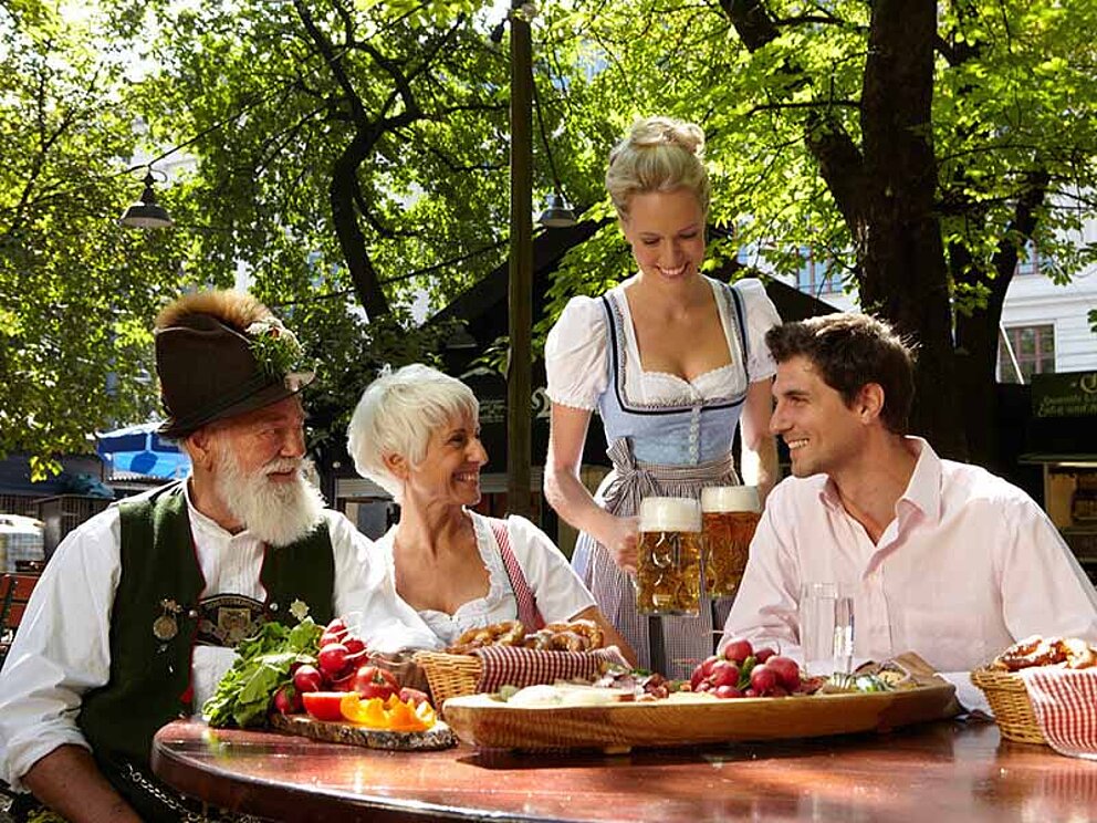 Besuch im Biergarten in München mit typisch-bayrischen Trachten-Kellner