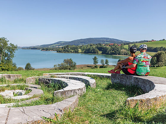 ein Paar sitzt auf Steinen und blickt auf den SEe
