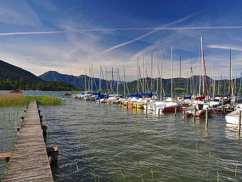 Blick vom Steg auf den Tegernsee mit einigen angelegten Booten