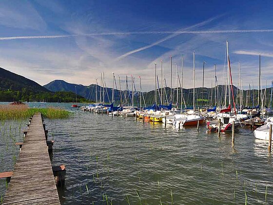 Blick vom Steg auf den Tegernsee mit einigen angelegten Booten