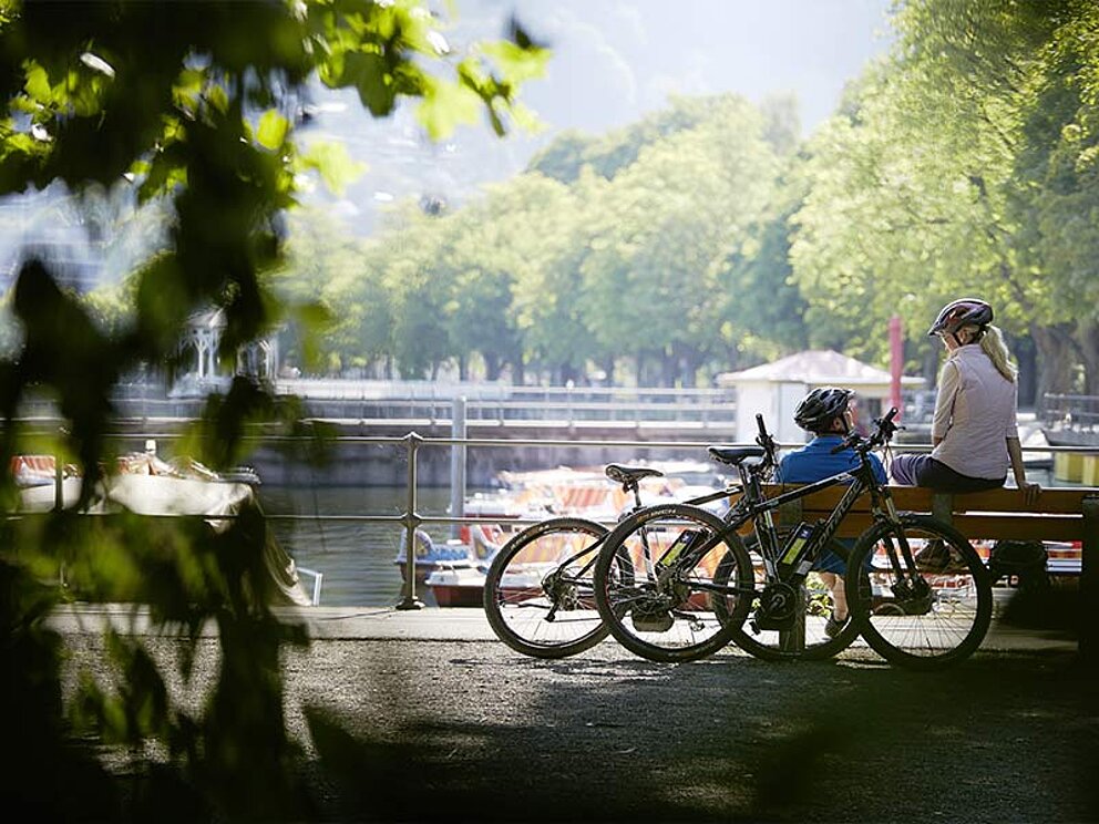 2 Radfahrer auf einer Parkbank am Bodensee-Ufer