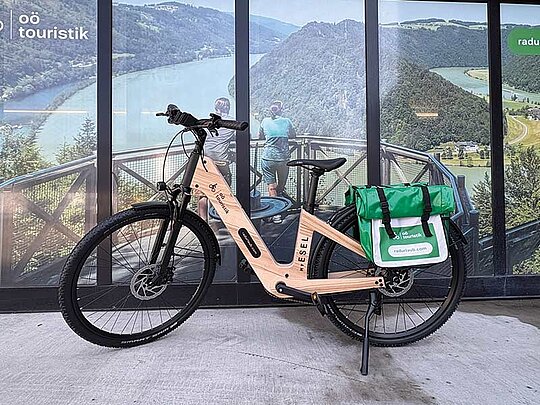 Das Leihrad aus Holz mit Satteltasche platziert vor dem Schaufenster der Radausgabe