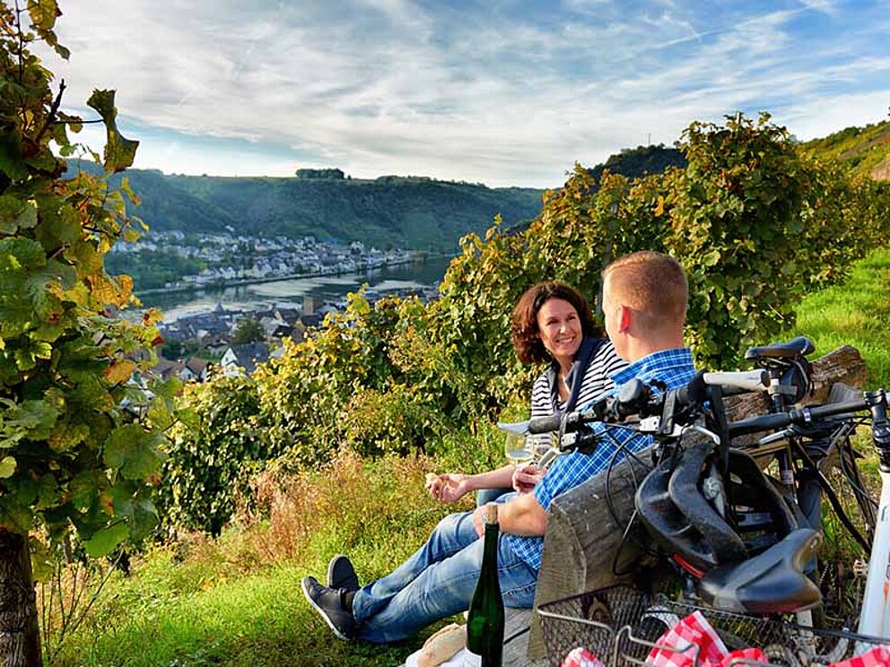 zwei Radfahrer auf Bank mit Blick auf die Weinberge und die Mosel