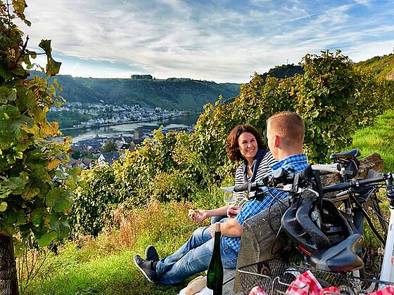 zwei Radfahrer auf Bank mit Blick auf die Weinberge und die Mosel