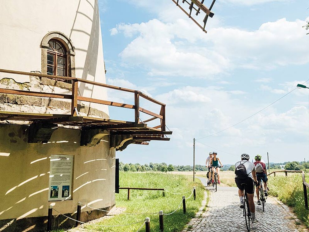Radfahrer fahren an der Windmühle vorbei