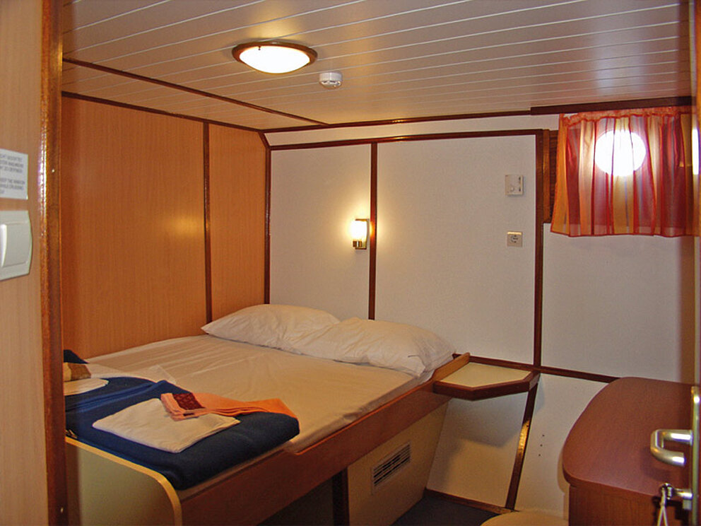 Kabine mit Doppelbett und kleinem Fenster