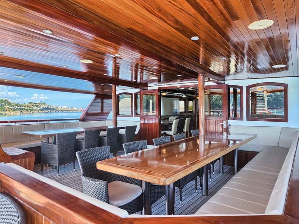 Unterdeck mit Loungebänken und Tischen.