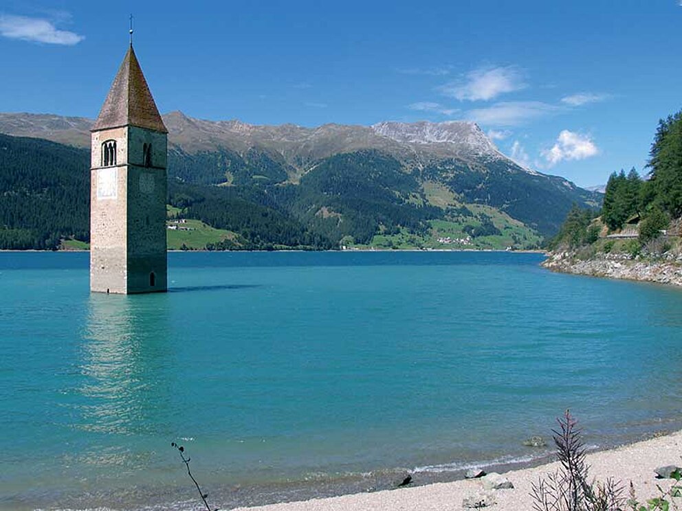 Aus dem Reschensee ragt nur noch der Kirchturm von Alt Grün. Der Rest des Dorfes wurde geflutet.