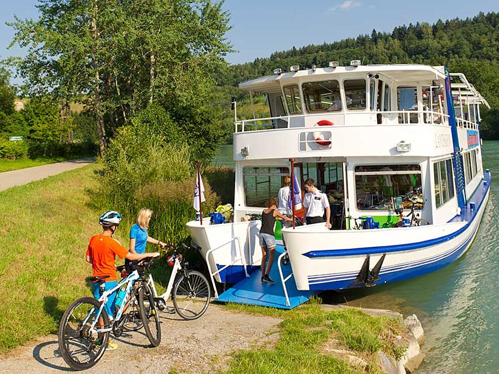 Radfahrer machen eine Bootsfahrt auf der Drau
