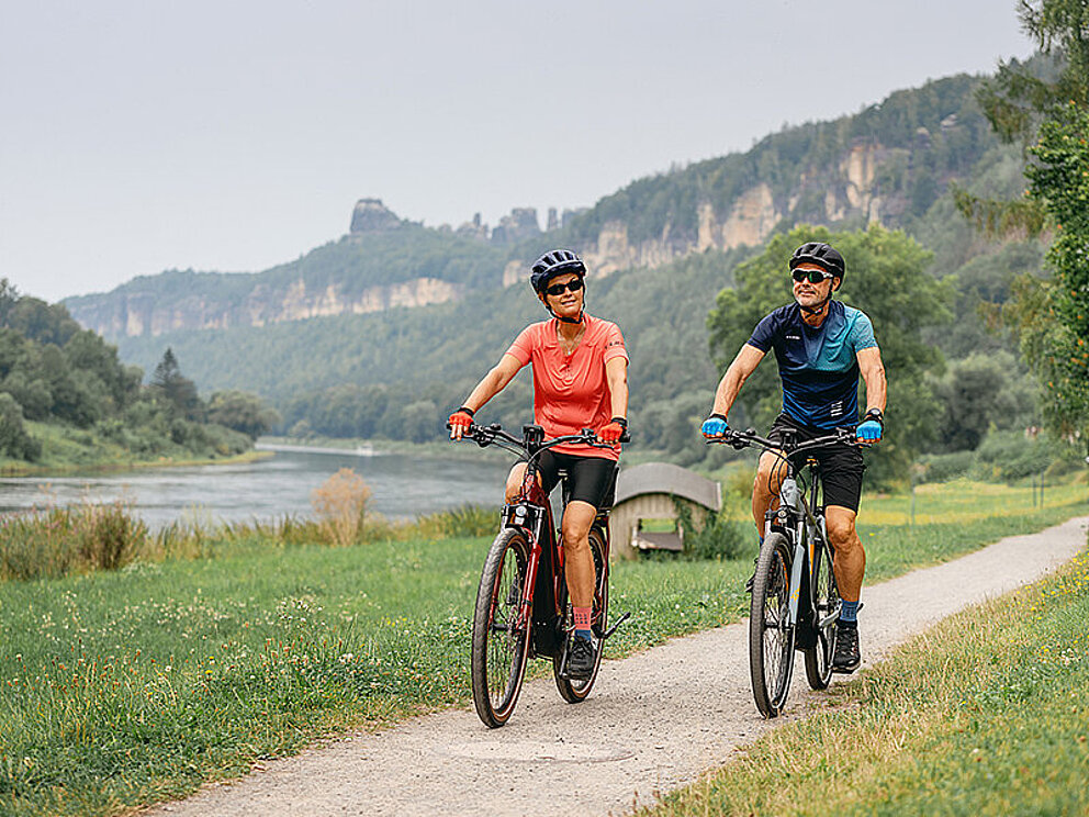 Am Ufer der Elbe radeln ein Mann und eine Frau