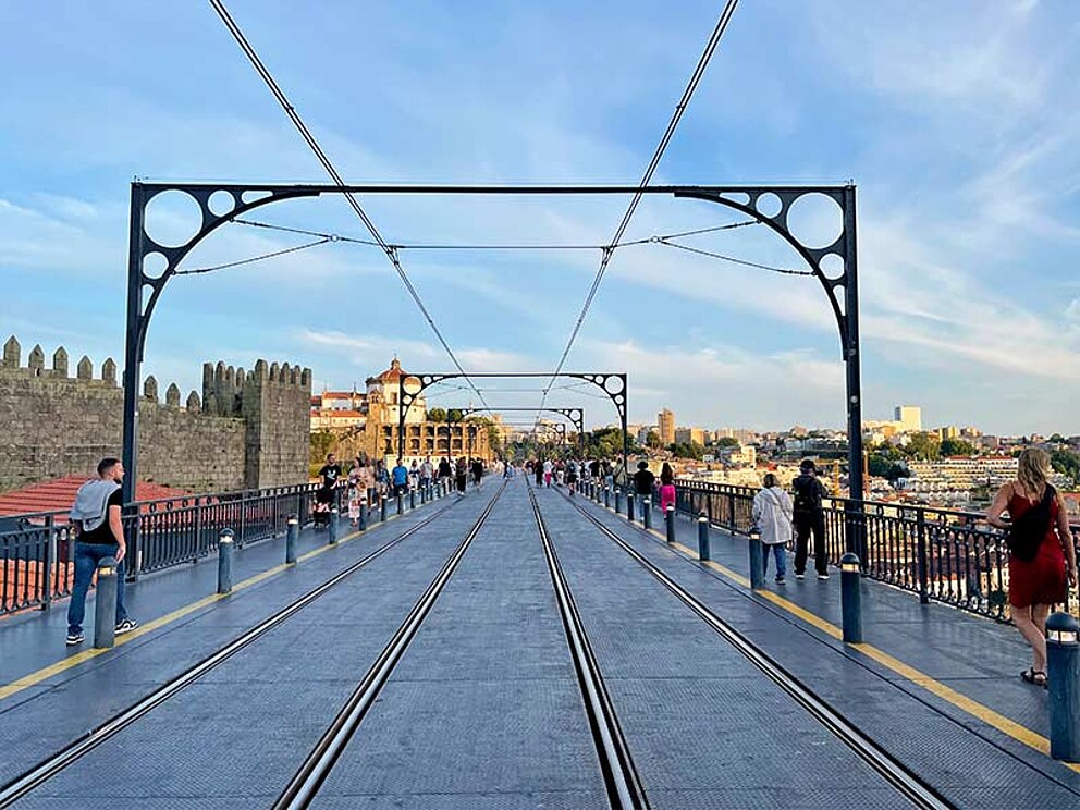 Brücke mit Straßenbahnschienen und Menschen, die an den Rändern die Brücke überqueren