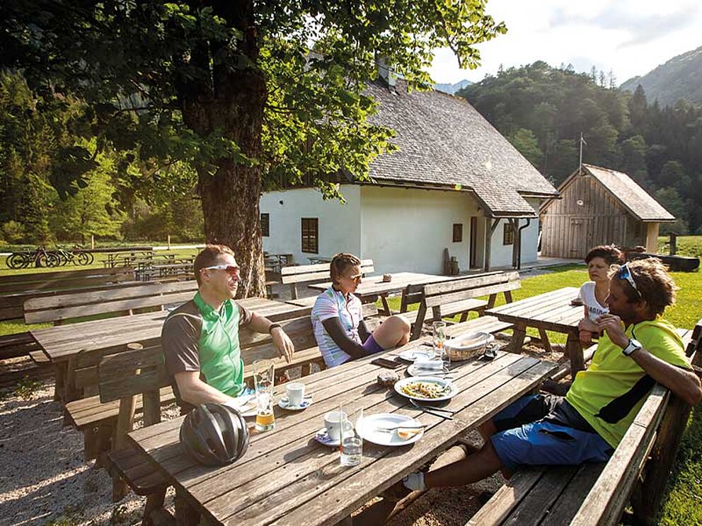 4 Biker sitzen am Gastgartentisch und genießen die Sonne
