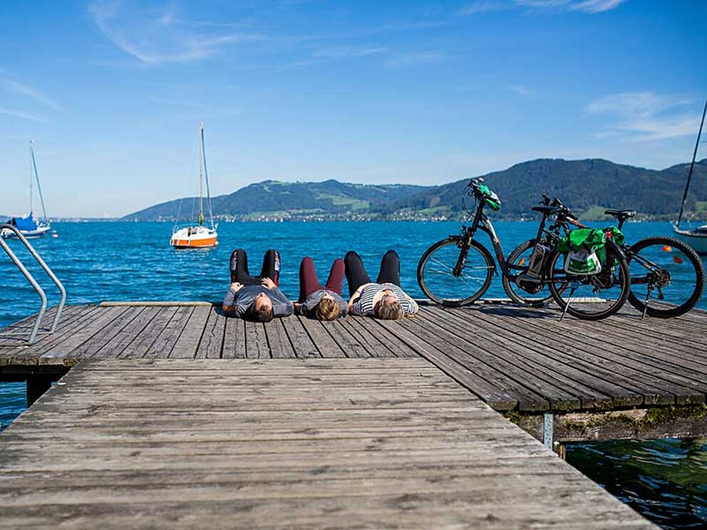 Familie mit Rädern liegen am Steg am Attersee