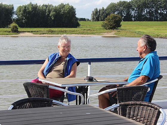 2 Männer sitzen bei Tisch am Oberdeck