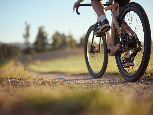 Eine Dame am Gravelbike auf einem Schotterweg