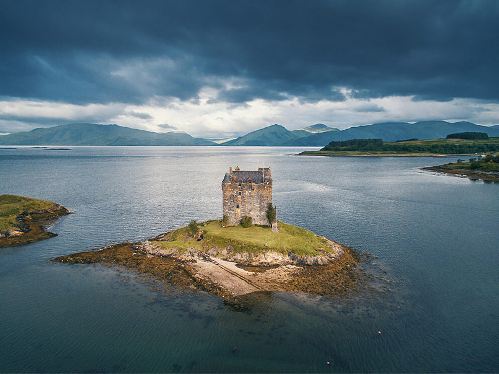 Blick auf eine kleine Insel im Loch Linnhe mit einem alten Schloss.