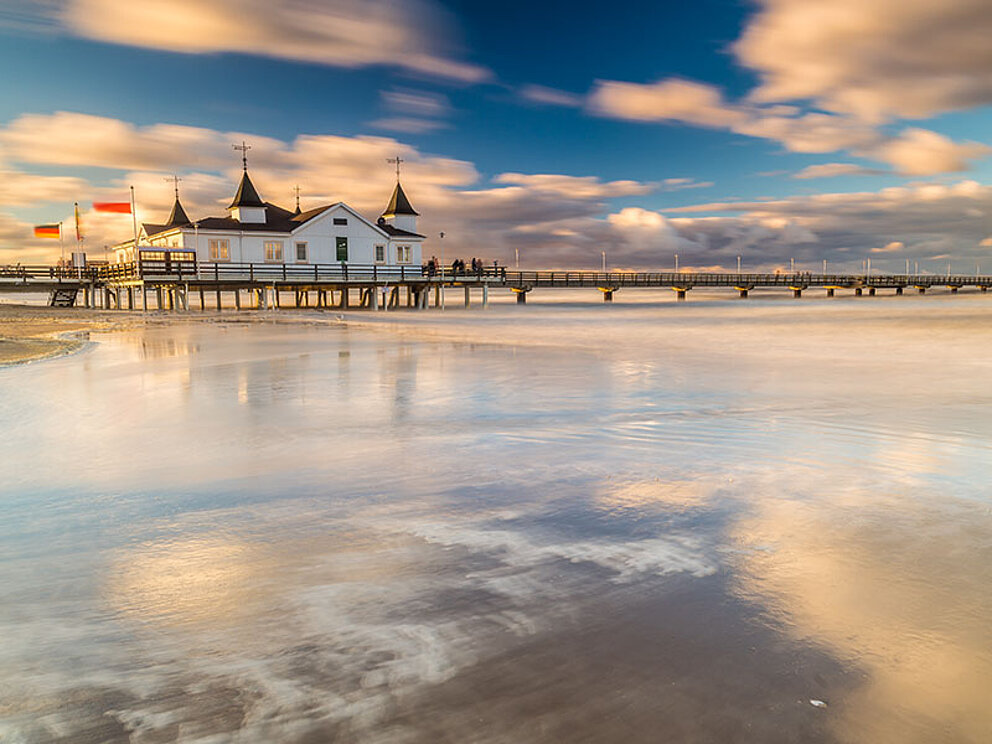 Küste mit Sandstrand, einer Seebrück mit Haus darauf
