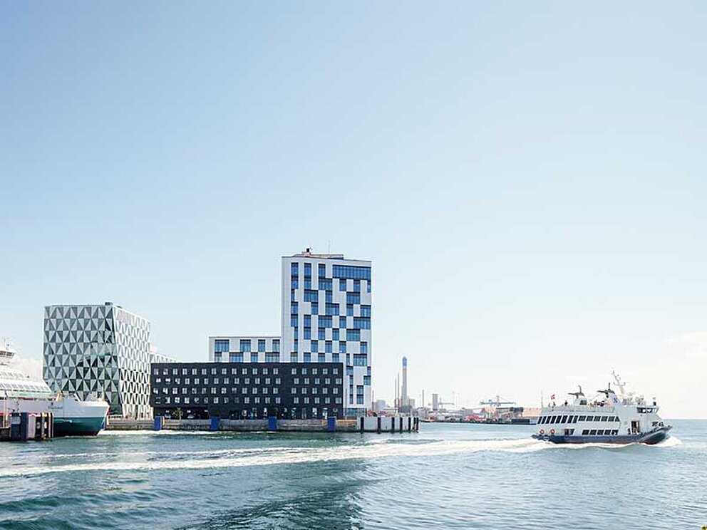 Der Hafen von Helsingborg mit Frachtschiff und Lotsenboot. Dahinter moderne Hochhäuser