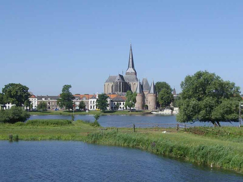 Die Kirche von Kampen in Holland liegt an einem Fluss umgeben von einem Park.