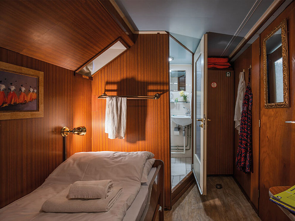 Kabine mit Einzelbett, kleiner Badezimmernische und Kästen