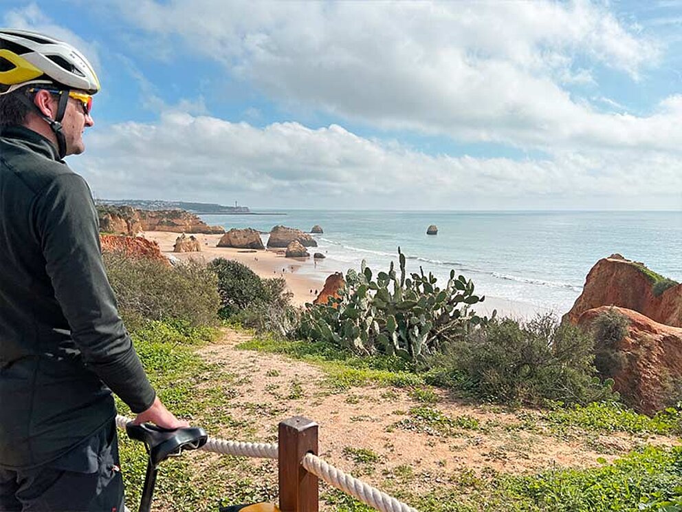 ein Mann blickt zur Küste mit Sandstrand und Felsen