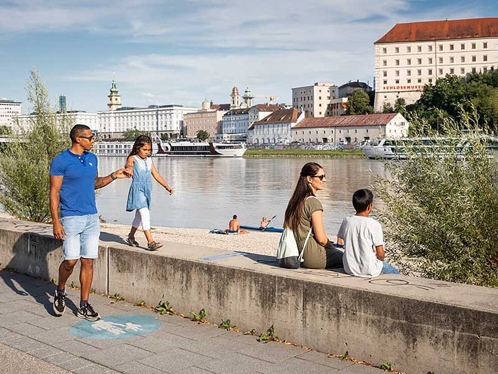 Familie genießt Sonne am Donau Ufer in Linz