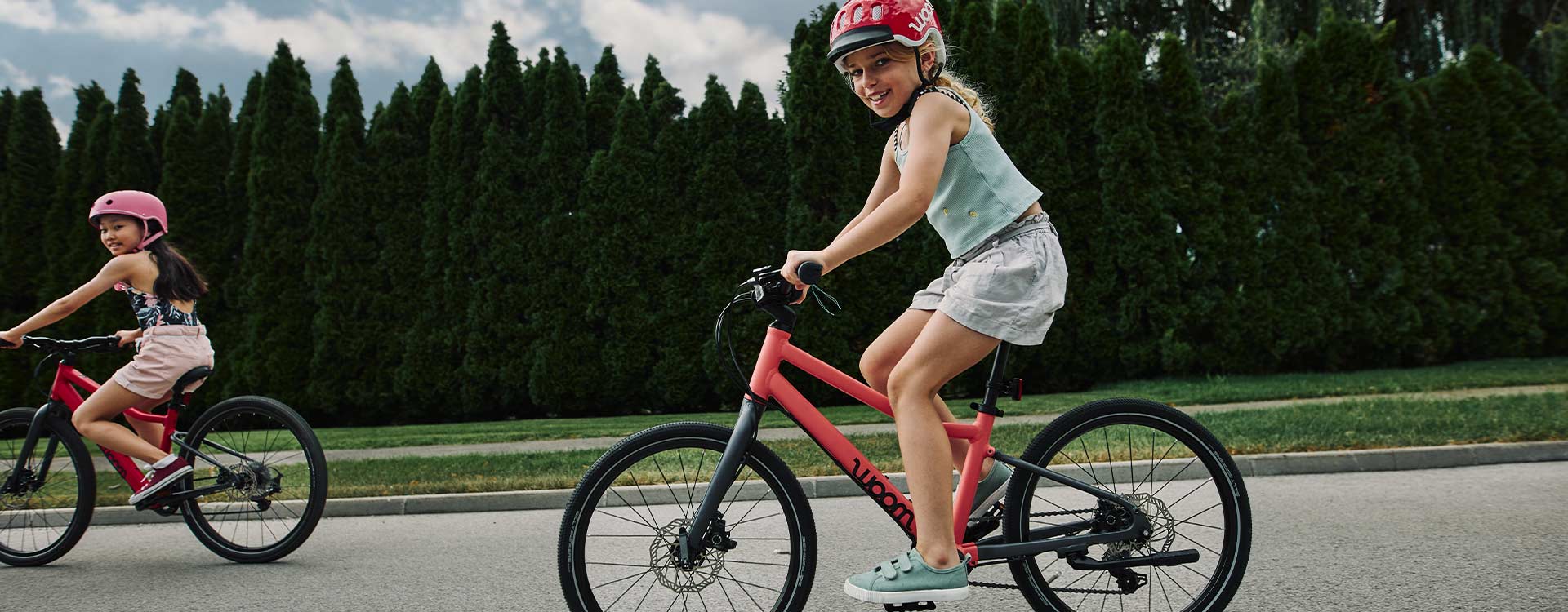 2 Mädchen auf Woom Fahrrädern am asphaltierten Radweg