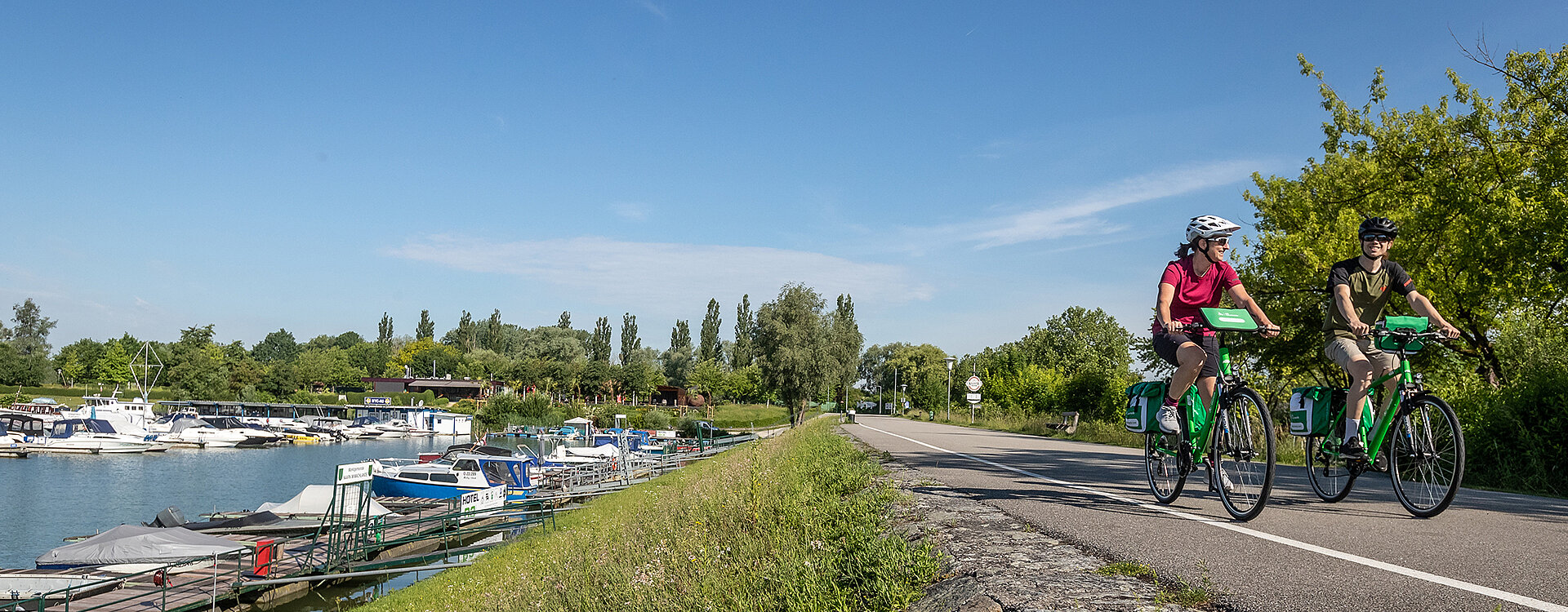 Radfahrer neben Booten und Yachten im Hafengelände