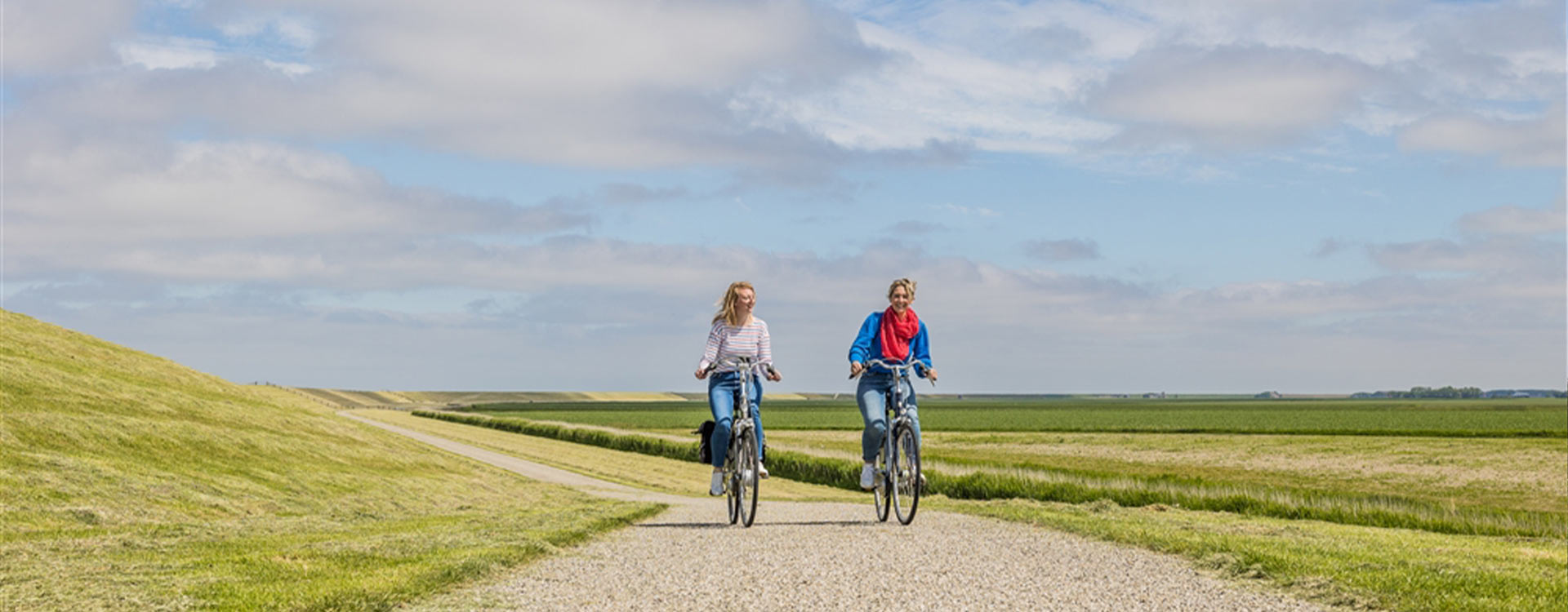 2 Radfahrer auf einem flachen Radweg, umgeben von unberührter Natur