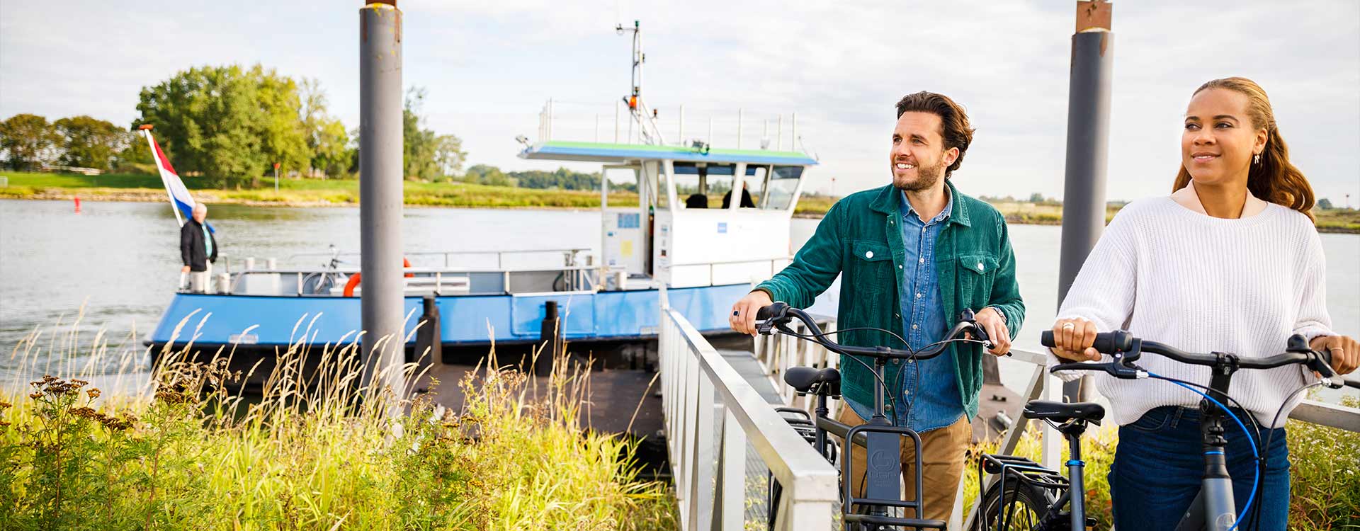 2 Radfahrer schieben ihr Rad vom Schiff über einen Steg.