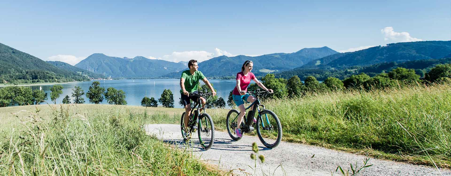 zwei Radfahrer radeln am Isarradweg vorbei am Tegernsee