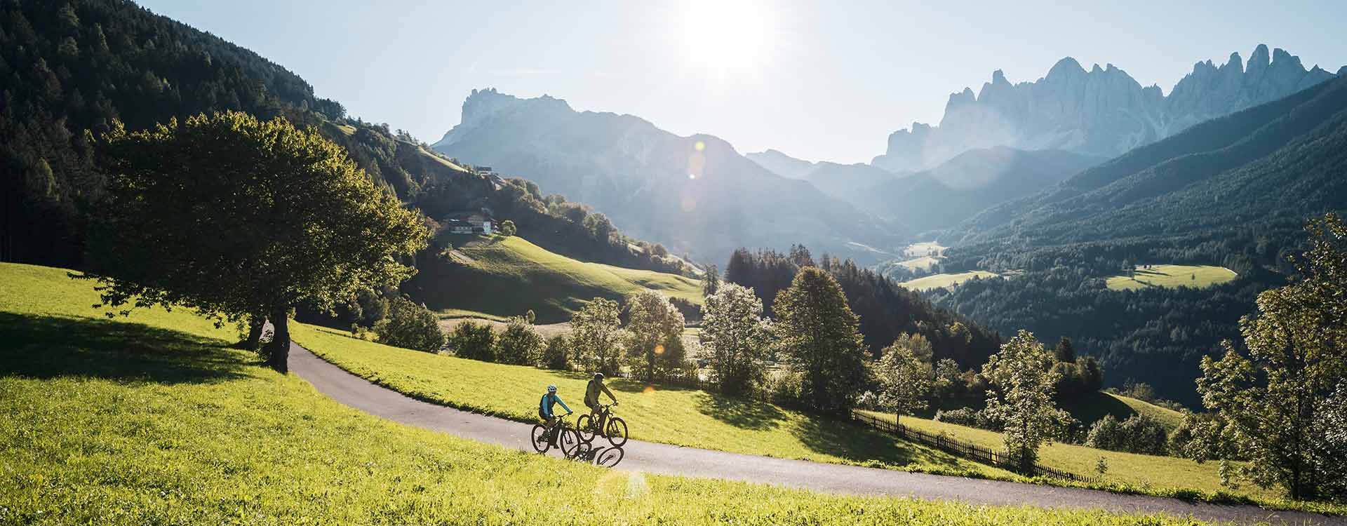 Bergpanorama in der Abendämmerung, davor 2 Radfahrer