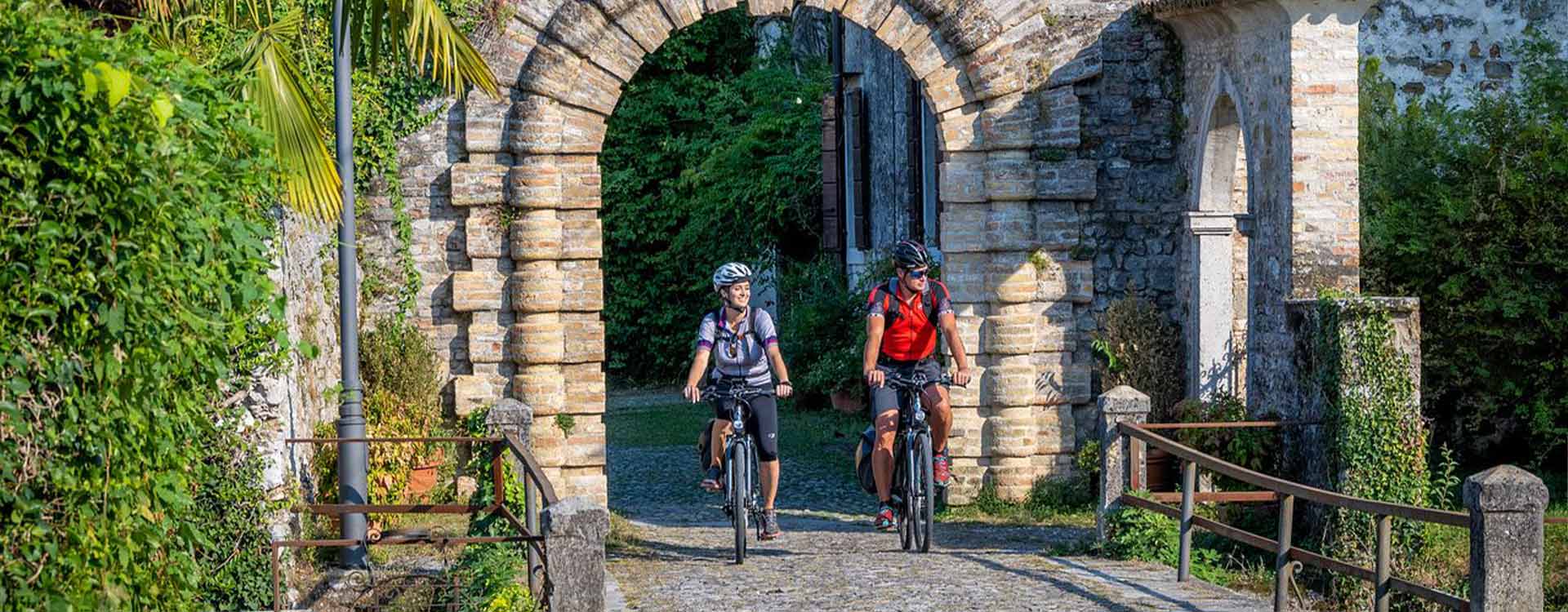2 Radfahrer fahren durch ein Tor in der italienischen Stadt Cervignano