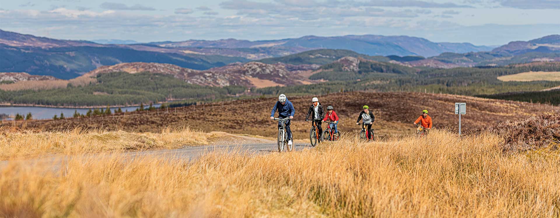 Eine Gruppe Radfahrer auf einer Straße mitten in unberührter schottischer Landschaft.