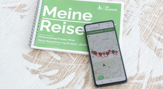 Reiseunterlagen-Routenbuch und geöffnete App am Mobiltelefon